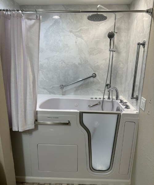 Walk in bathtub with frosted door grab bars rainfall and handheld shower in marble alcove