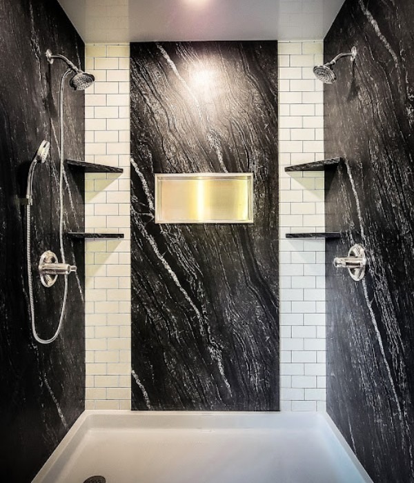 Contemporary shower with black stone panels white subway tiles dual showerheads and recessed niche