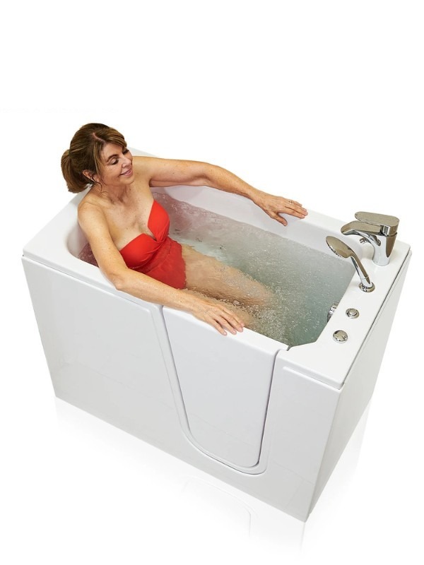 Woman in red swimsuit relaxing in a compact white walk in bathtub with chrome fixtures and gentle jets